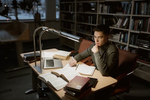 a person studying at a desk surrounded by books and a laptop